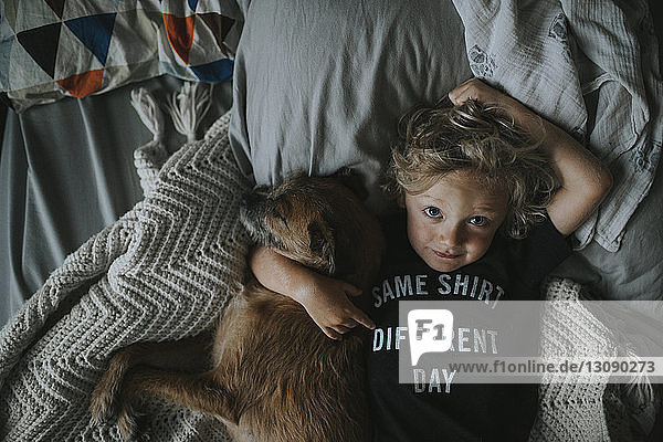 Bildnis eines Jungen mit Hund auf dem Bett liegend