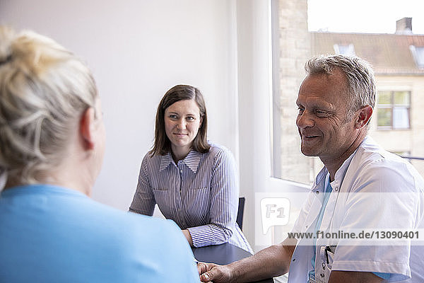 Doctors discussing while sitting with female patient in medical clinic