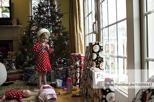 Mädchen steht zu Hause am Weihnachtsbaum