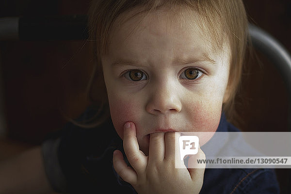 Nahaufnahme-Porträt eines süßen Mädchens mit Fingern im Mund zu Hause