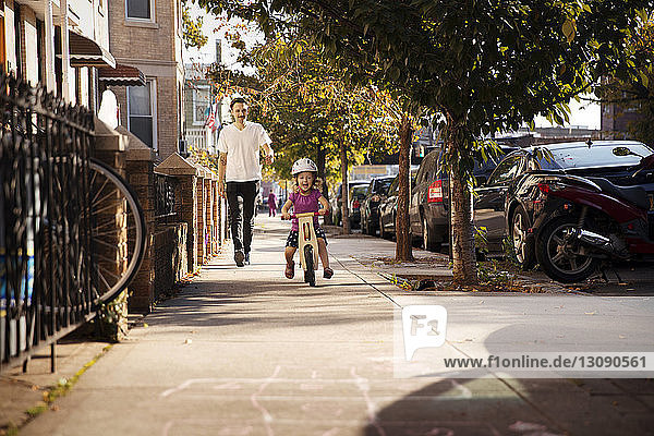 Vater schaut Tochter beim Radfahren auf dem Fußweg an