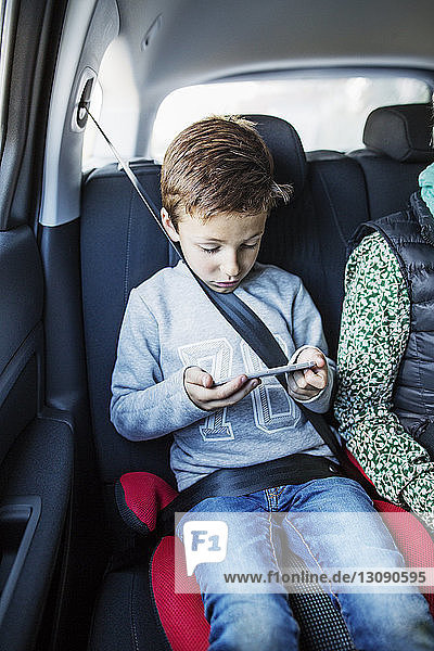 Boy using smart phone in car