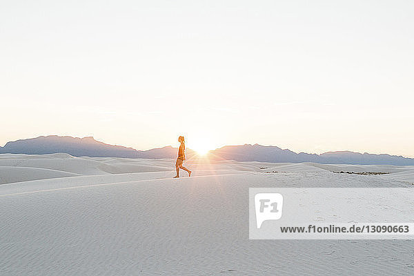 Seitenansicht einer Frau beim Spaziergang am White Sands National Monument vor klarem Himmel bei Sonnenuntergang
