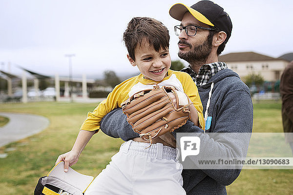 Vater trägt glücklichen Sohn im Stehen auf Sportplatz