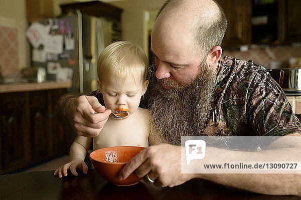 Vater gibt dem Sohn Suppe am Esstisch