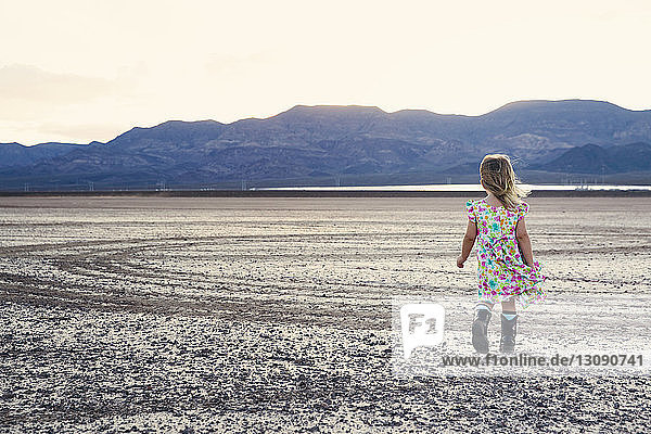 Rear view of girl walking on arid landscape