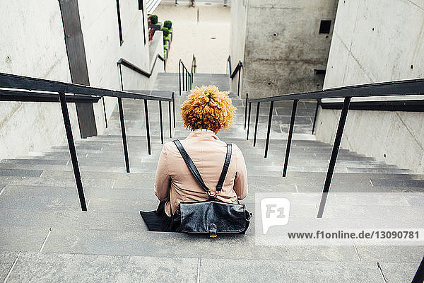 Rear view of woman with bag sitting on steps
