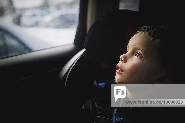 Nachdenklicher Junge schaut auf  während er im Auto unterwegs ist