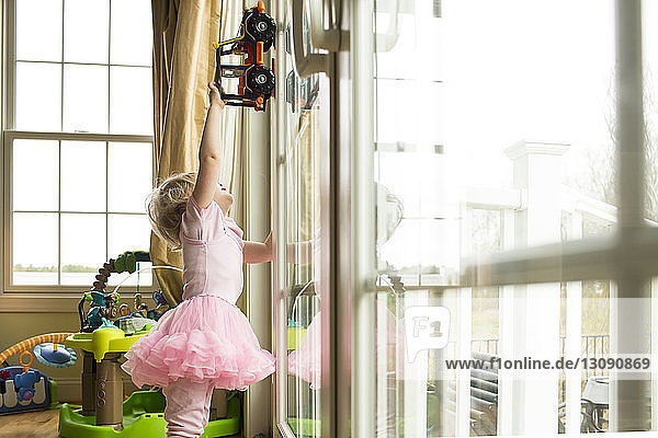 Girl playing with toy car on window at home