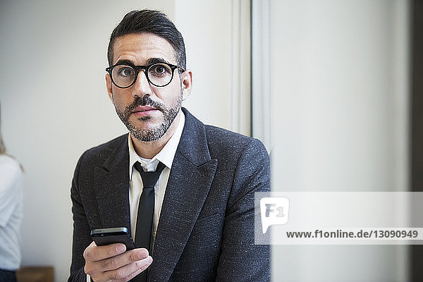 Portrait of businessman using phone in office