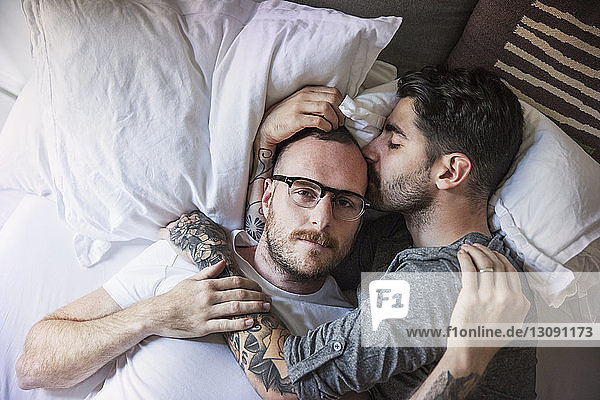 Mann küsst Freund  während er zu Hause auf dem Bett liegt