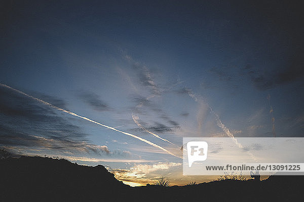 Scherenschnitt eines Mannes  der bei Sonnenuntergang auf dem Feld gegen den Himmel steht