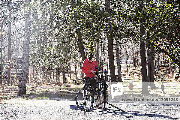 Sportler  der bei Sonnenschein sein Fahrrad auf der Straße einstellt