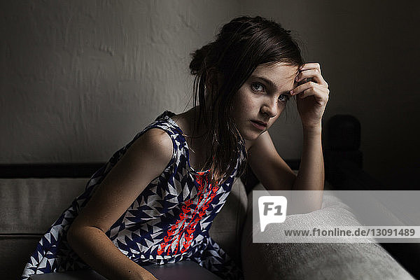 Bildnis eines traurigen Mädchens mit Kopf in der Hand in der Dunkelkammer sitzend