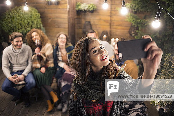 Woman taking selfie with friends in backyard at night