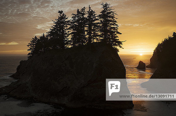 Landschaftliche Ansicht der Silhouetten von Felsformationen und des Meeres gegen den Himmel bei Sonnenuntergang