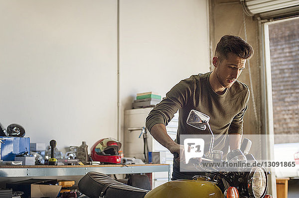 Man examining motorcycle in garage