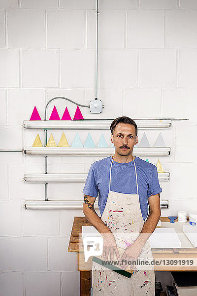 Portrait of worker standing by workbench in workshop