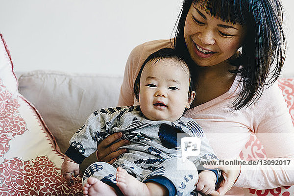 Happy mother with cute son sitting on sofa at home