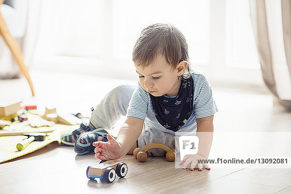 Baby boy playing with toys while sitting on floor at home