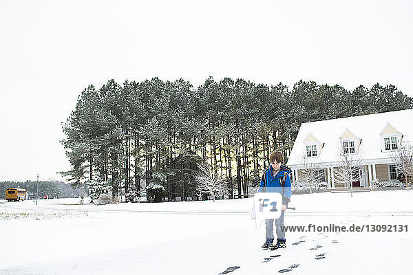 Junge geht auf schneebedecktem Feld gegen klaren Himmel