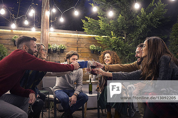 Glückliche Freunde stoßen bei einer Party im Hinterhof auf Getränke an