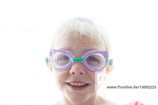 Portrait of smiling girl wearing swimming goggles against sky during sunny day