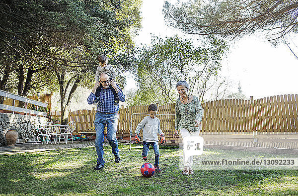 Großeltern und Enkel in voller Länge beim Fußballspielen auf dem Hof