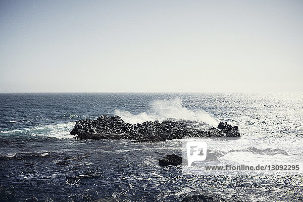 Wellen plätschern auf Felsen im Meer gegen klaren Himmel