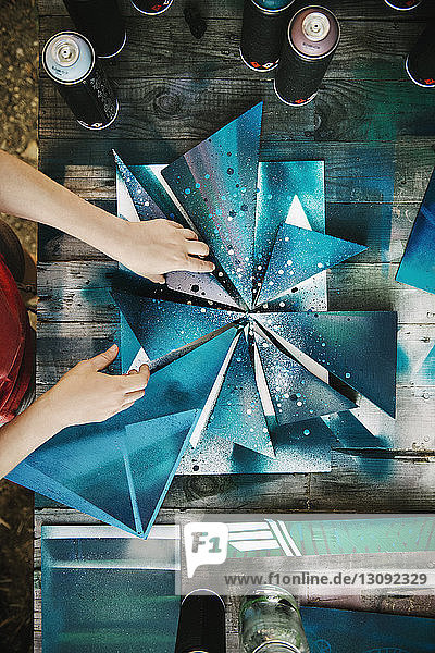 Overhead view of female artist arranging art work at table