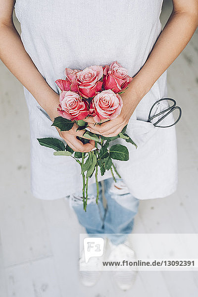 Hochwinkelansicht eines Floristen mit rosa Rosen im Blumenladen