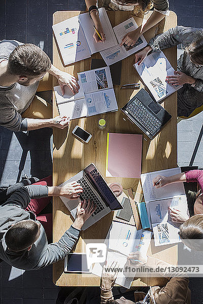 Overhead view of friends studying at table in college