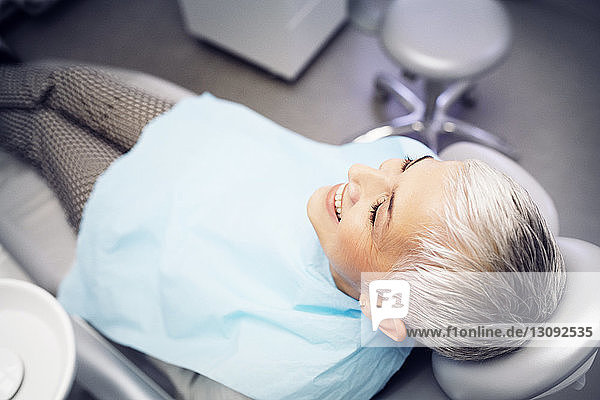 High angle view of smiling woman sitting on dentist's chair