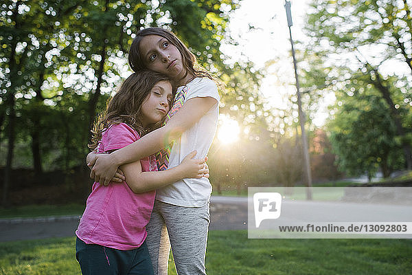 Sisters embracing while standing at park