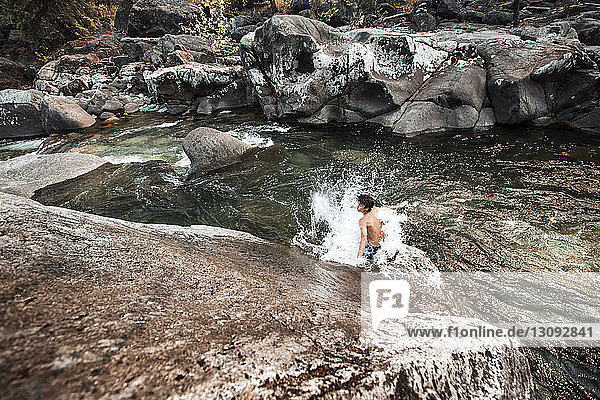 Hiker enjoying in river against rocks at forest