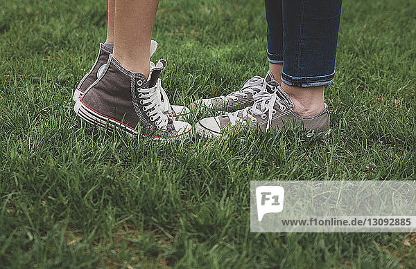 Niedrige Sektion von Mutter und Sohn mit Schuhen  während sie auf einem Grasfeld im Park stehen