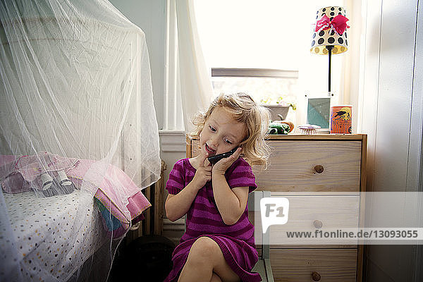 Playful girl using mobile phone while playing at home