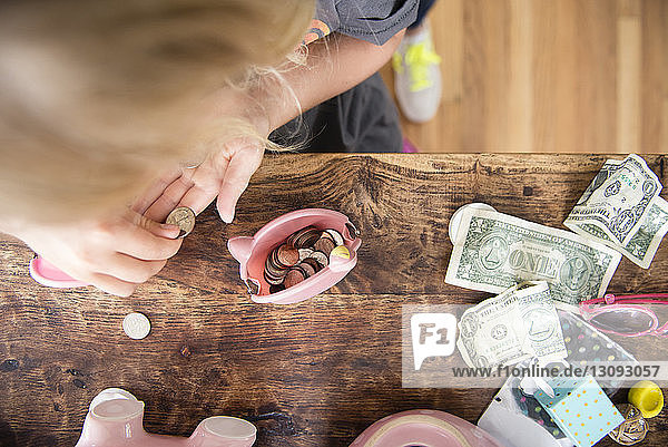 Mädchen zählt Geld  während sie zu Hause an einem Holztisch steht