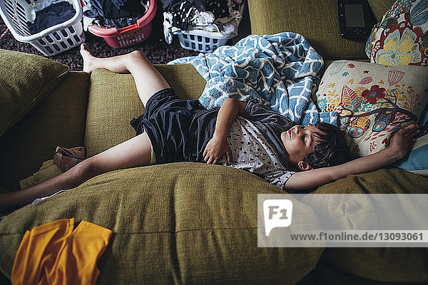 Draufsicht auf einen Jungen  der zu Hause auf einem schmutzigen Sofa schläft