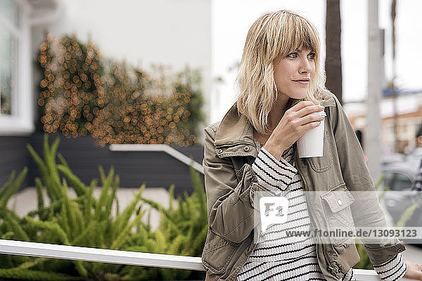 Nachdenkliche junge Frau trinkt Kaffee im Freien