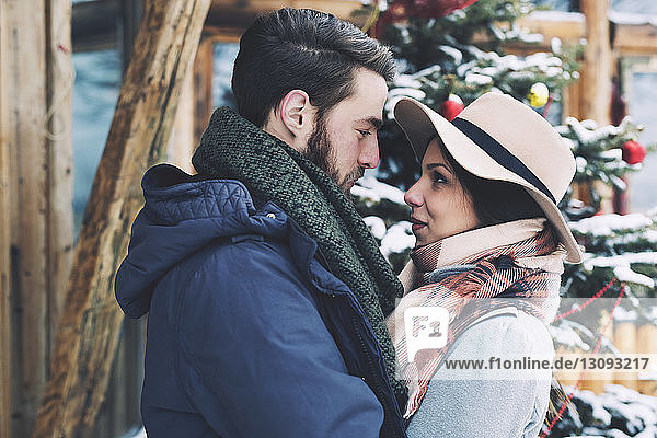 Romantic couple looking at each other while standing by Christmas tree