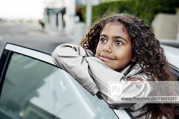 Nachdenkliches Mädchen lehnt an Autotür
