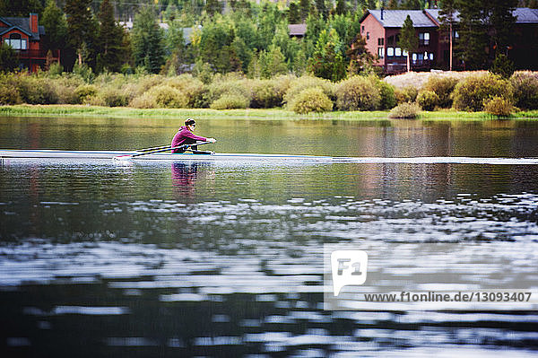 Seitenansicht einer Frau beim Kajakfahren auf einem See bei Bäumen