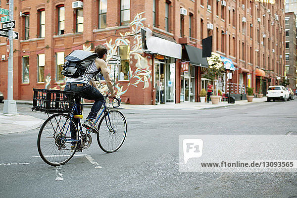 Mann mit Rucksack fährt Fahrrad auf Stadtstraße
