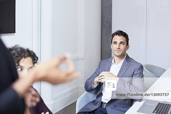 Businessman listening to colleagues in meeting at creative office