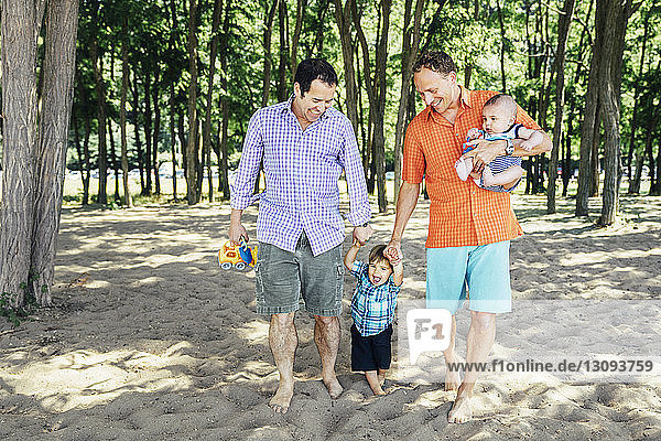 Homosexuelles Coupé mit Söhnen am Strand spazieren