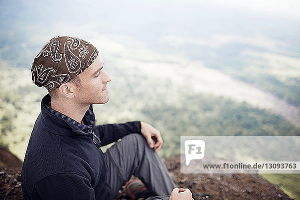 Mann meditiert im Sitzen auf Berg
