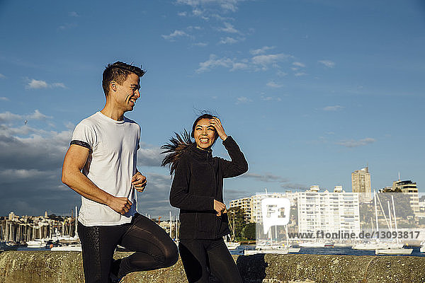 Glückliches junges Paar übt auf Promenade gegen den Himmel in der Stadt