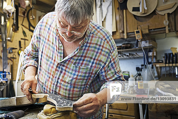 Male carpenter holding guitar while working in workshop
