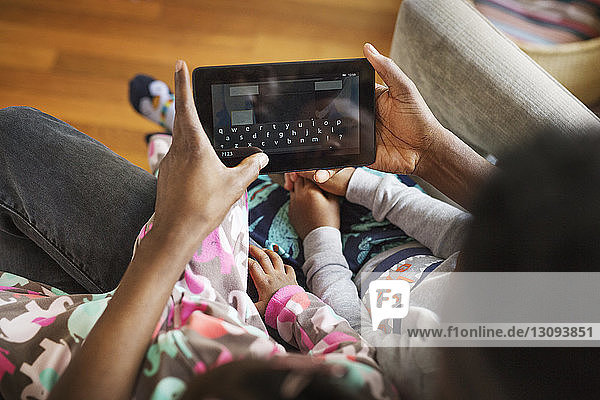 Draufsicht eines Vaters  der einen Tablet-Computer mit Kindern zu Hause benutzt